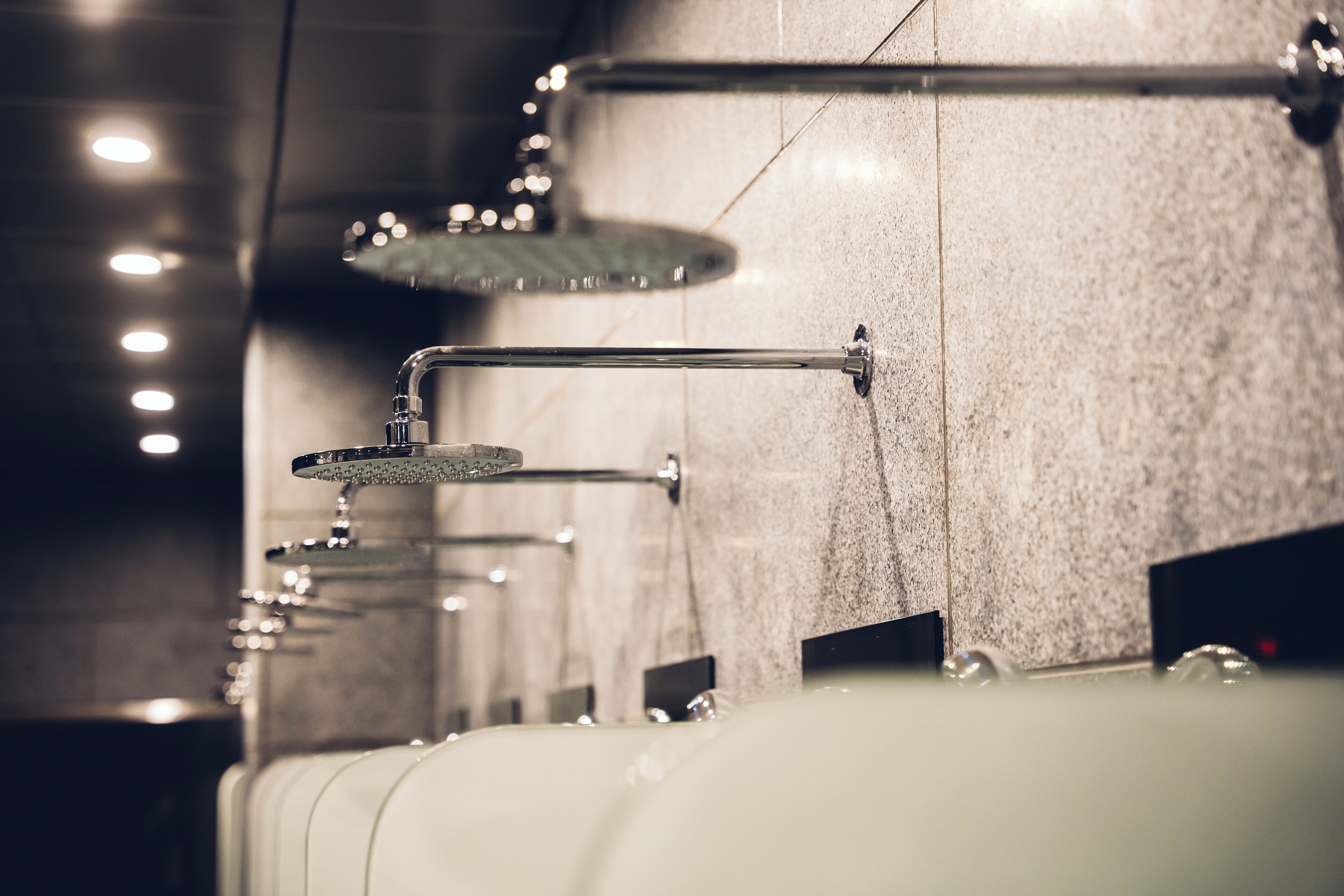 A modern bathroom with multiple showerheads and a marble wall.