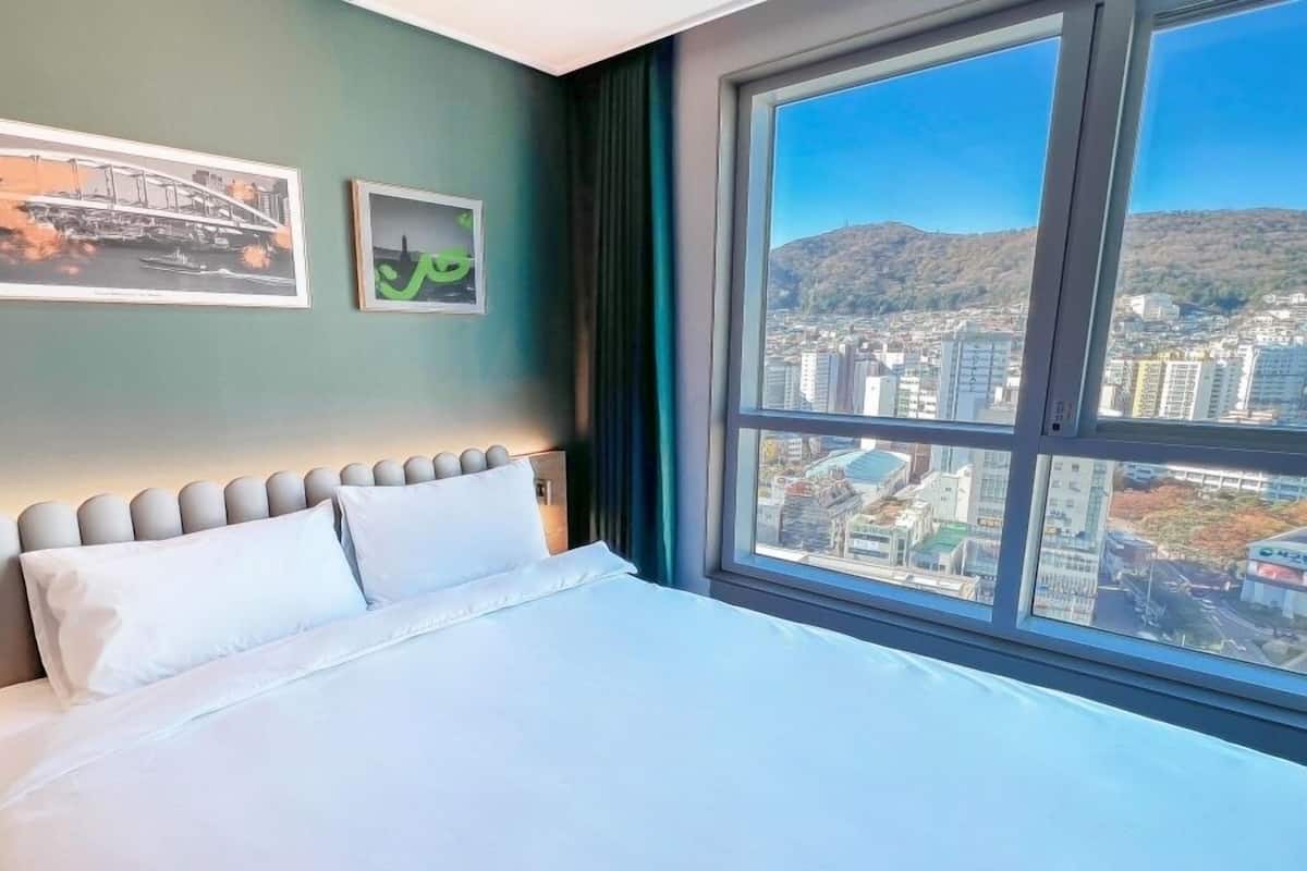 Una habitación de hotel con una cama grande, vistas a la ciudad y dos cuadros en la pared.
