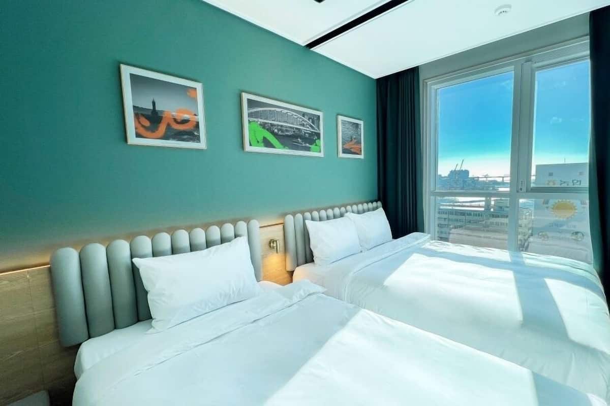 Habitación de hotel con una cama grande, dos almohadas, un cabecero y una ventana con vista a la ciudad.