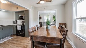 Une cuisine moderne avec des meubles gris, un réfrigérateur noir et une table à manger en bois, assortie de chaises.