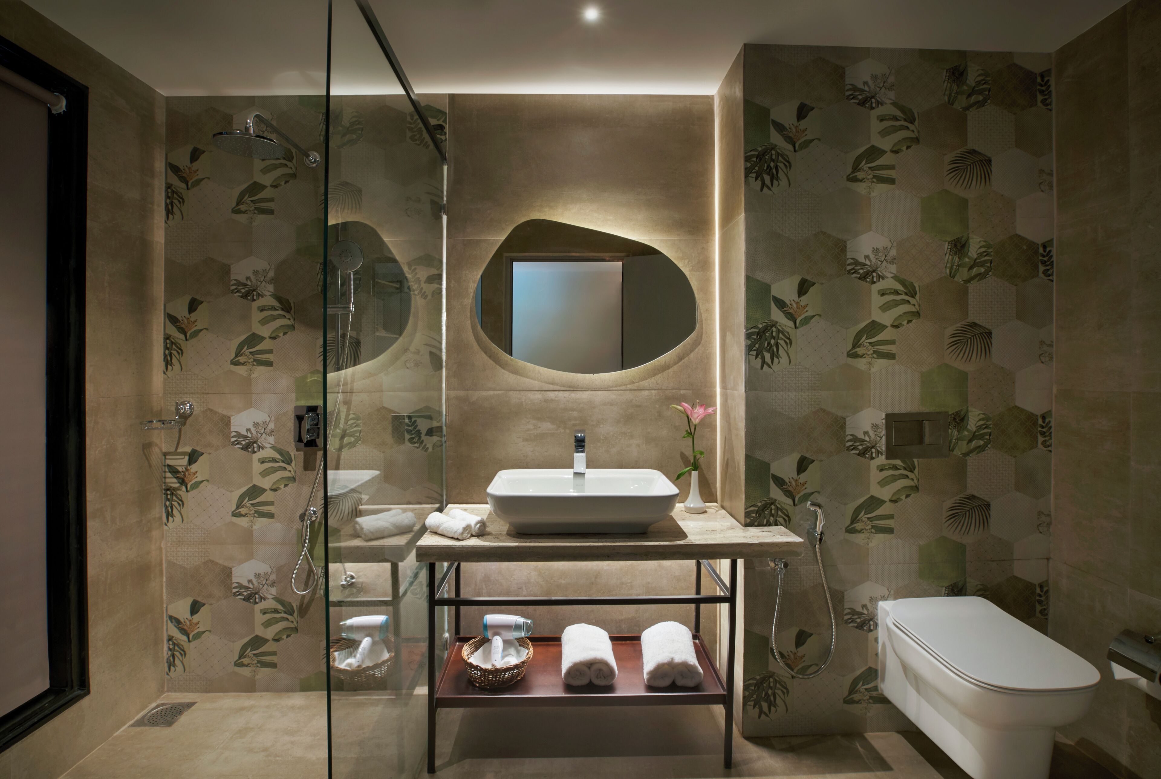 Un baño moderno con ducha de vidrio, un lavamanos con espejo y un inodoro.