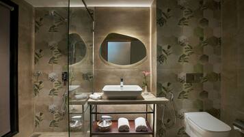 A modern bathroom with a glass-enclosed shower, a sink with a mirror above, and a toilet.