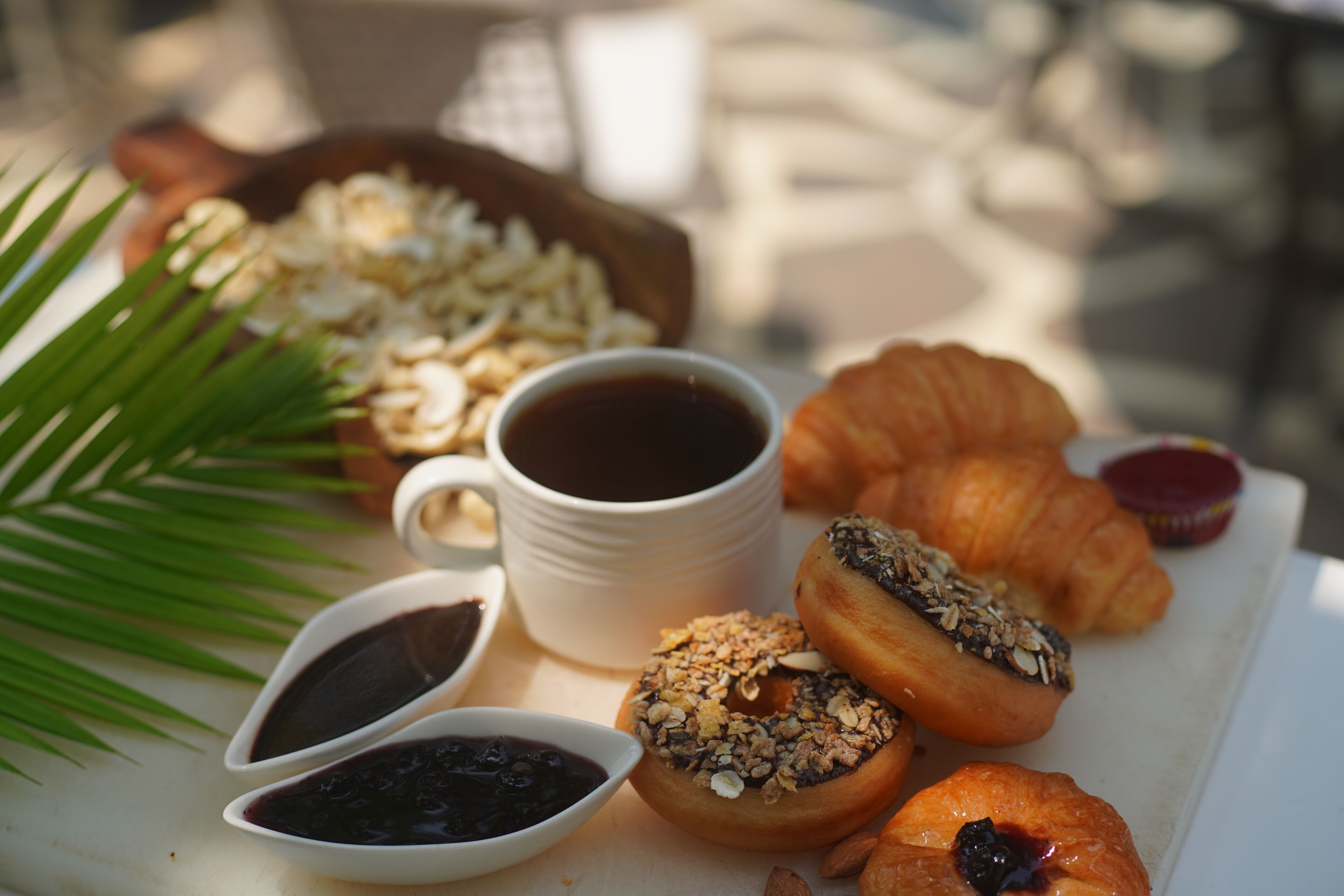 Un desayuno con cruasanes, granola, café y mermelada.