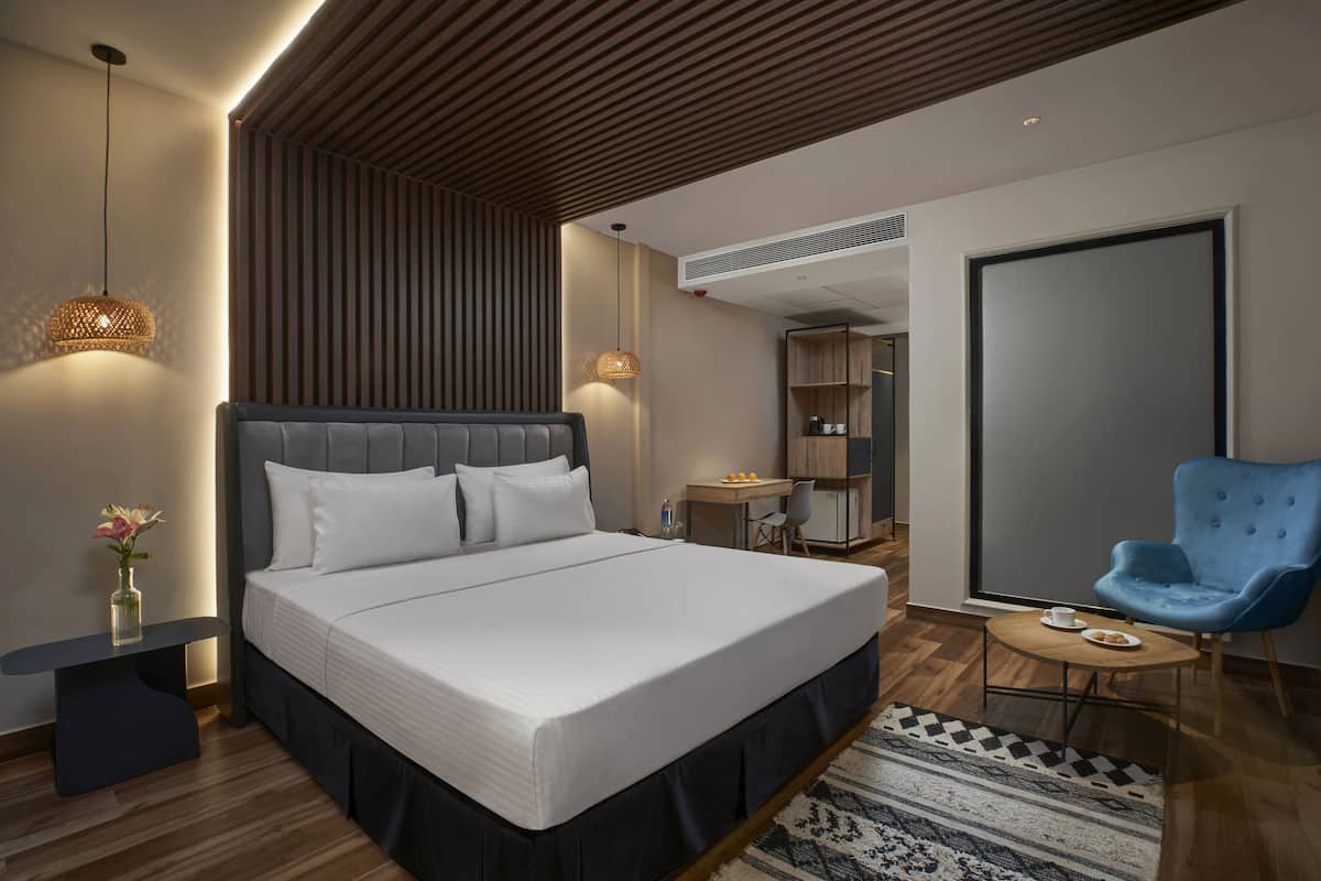 Una habitación de hotel moderna con una cama grande, un escritorio, una silla y un armario.