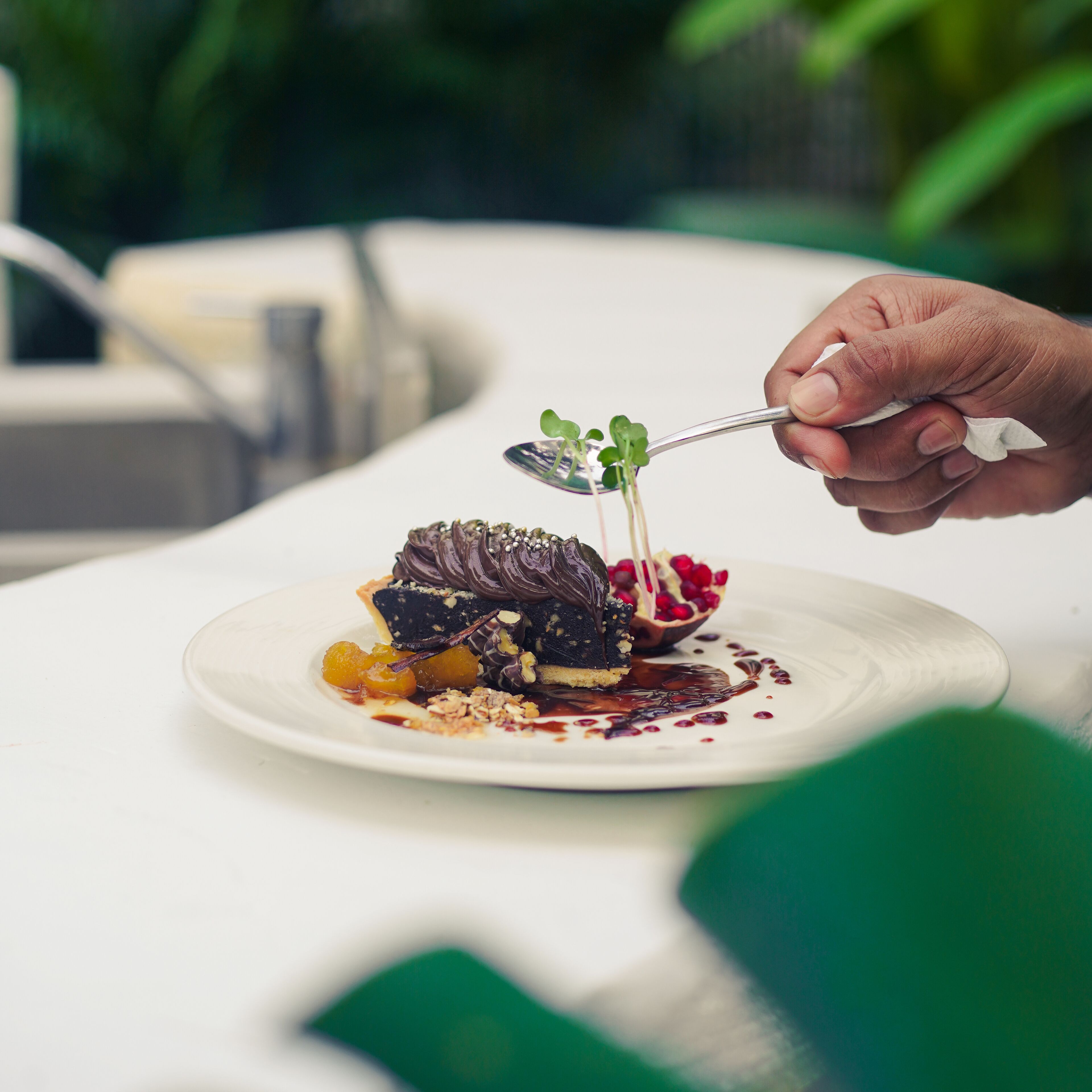 A dessert on a white plate with a spoon, garnished with green leaves and berries.