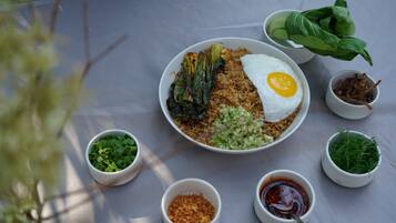 Una mesa con comida que incluye arroz, verduras y un huevo frito.
