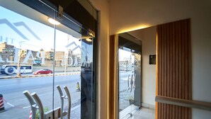 Entrada de hotel con puerta de cristal, panel de pared de madera y vista a la calle.