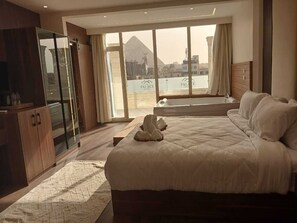 A bedroom with a large bed, a wooden wardrobe, and a view of a mountain through large windows.