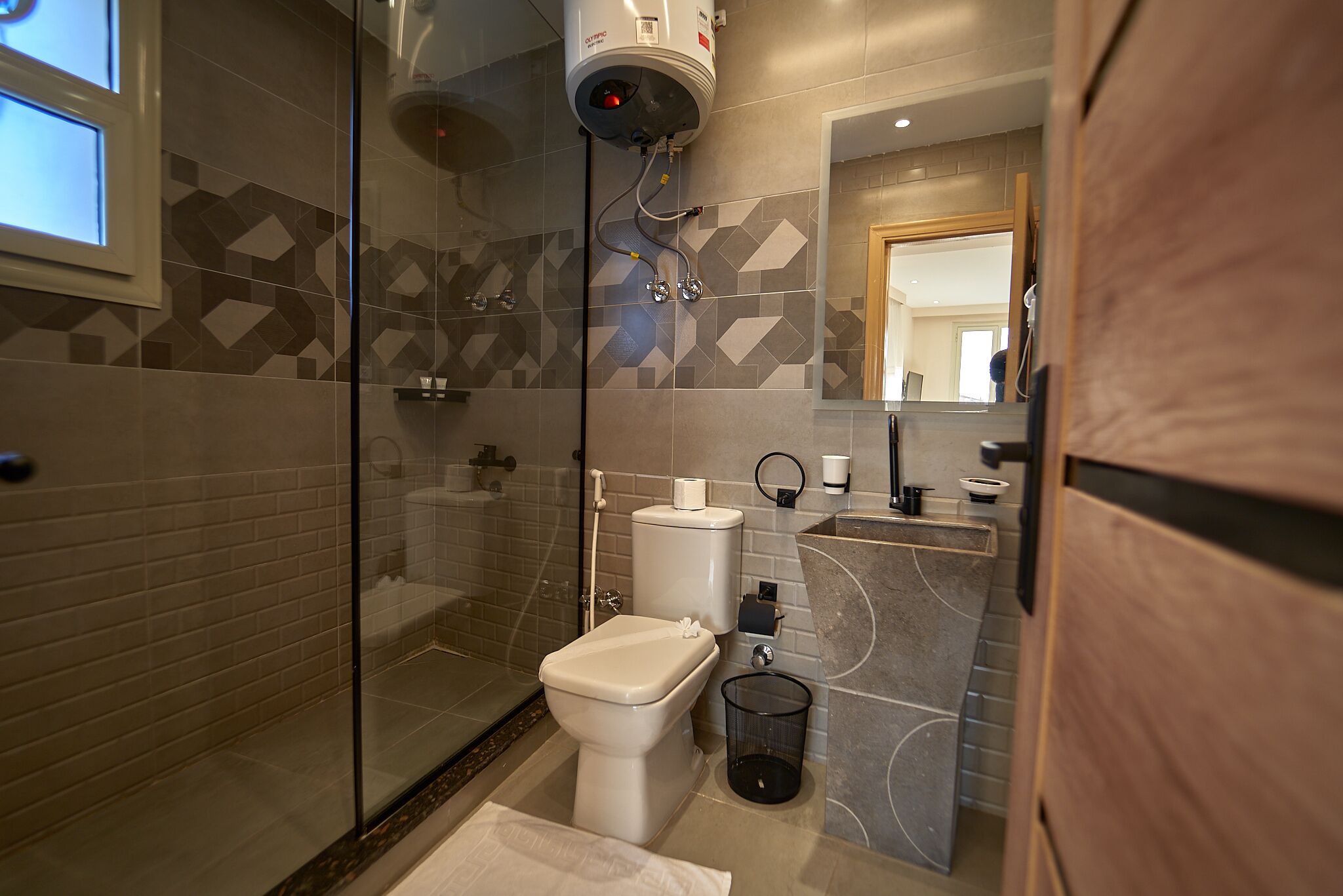 A modern bathroom with a glass shower enclosure, a toilet, and a sink with a mirror.
