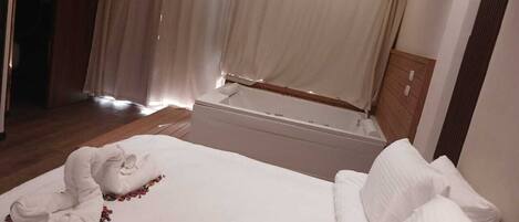 Una habitación de hotel con una cama grande, una zona de estar separada y vistas al exterior.