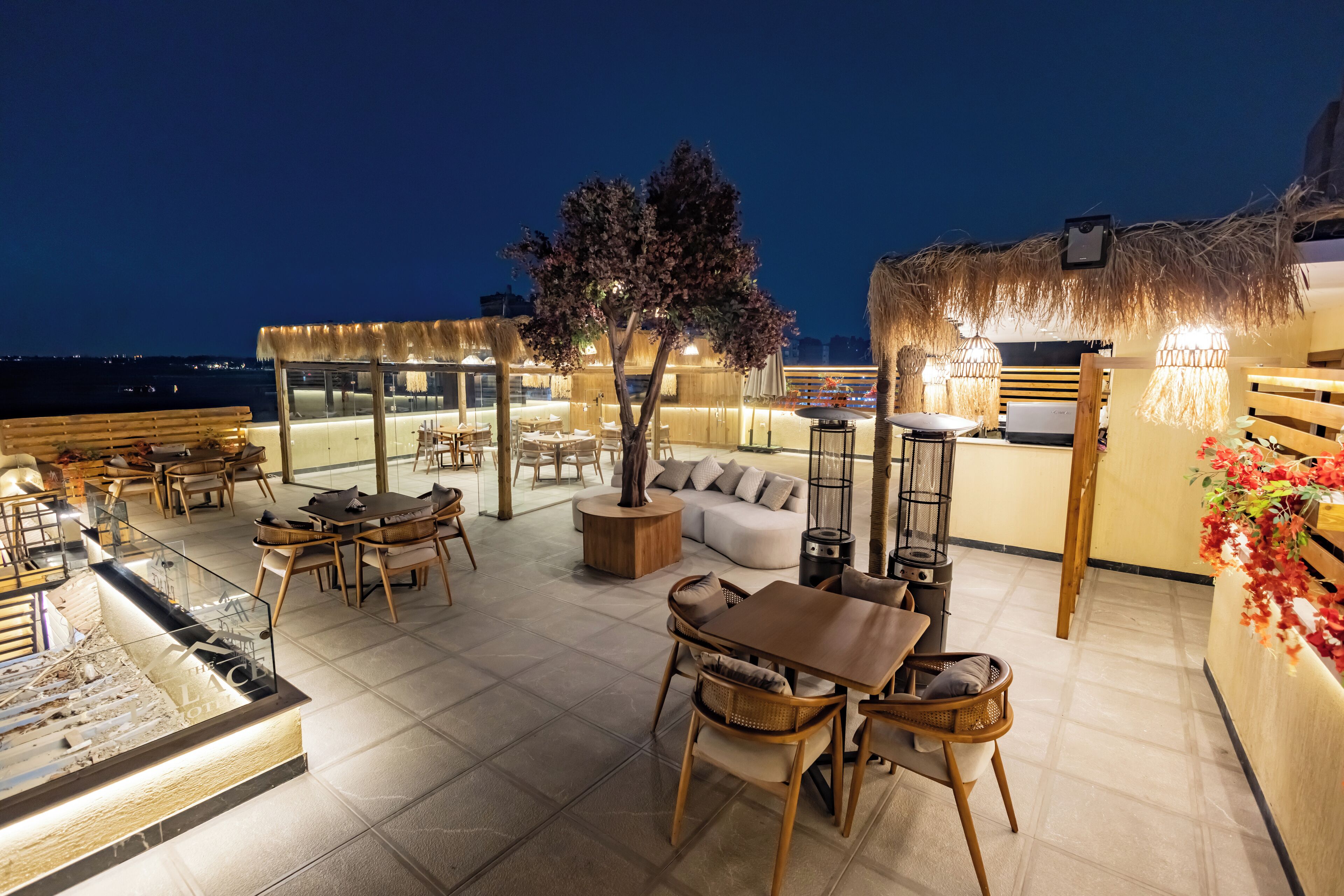 A rooftop bar with seating and a bar area, overlooking a body of water.