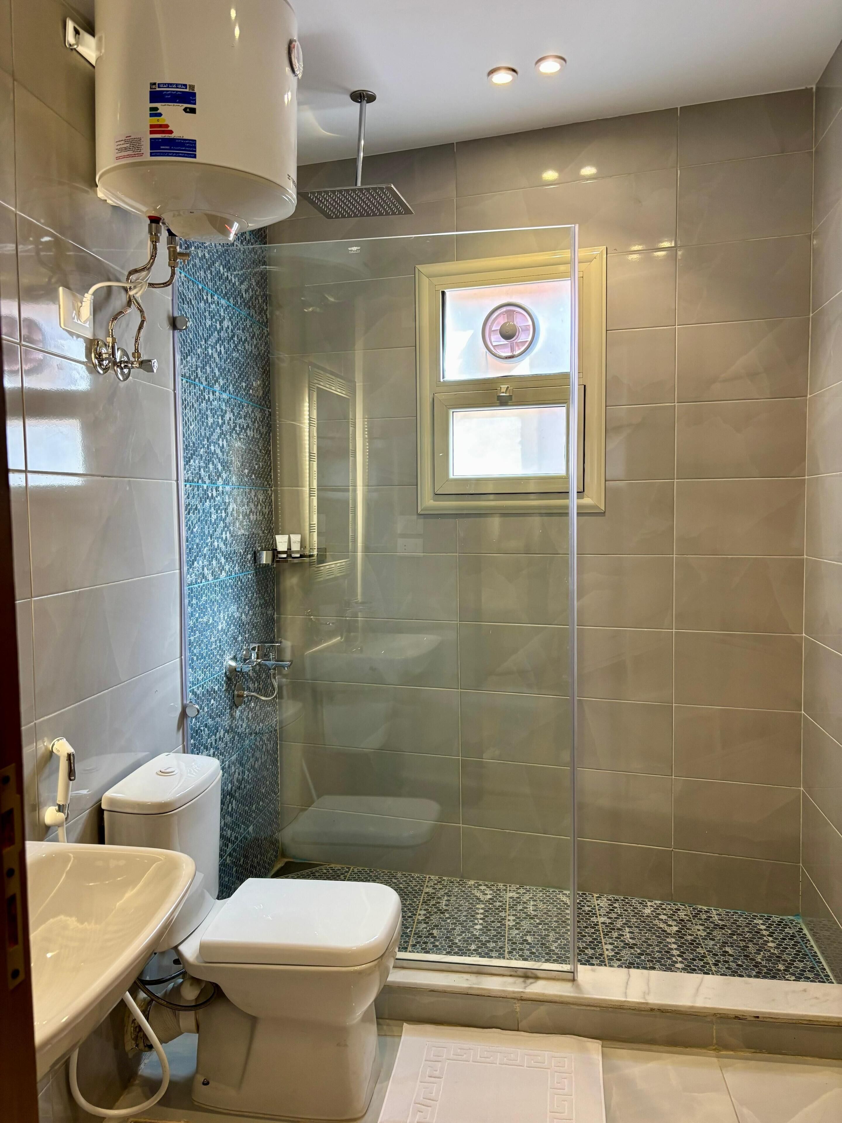 Een moderne badkamer met een glazen douchecabine, toilet en wastafel.