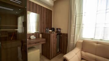 Una habitación de hotel moderna con un escritorio de madera, un sofá y un ventanal con cortinas.