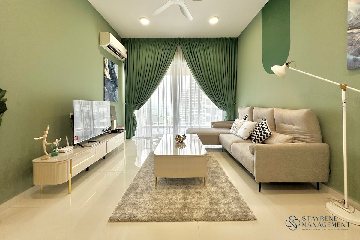 A modern living room with a flat-screen TV, a beige sofa, a coffee table, and a floor lamp.