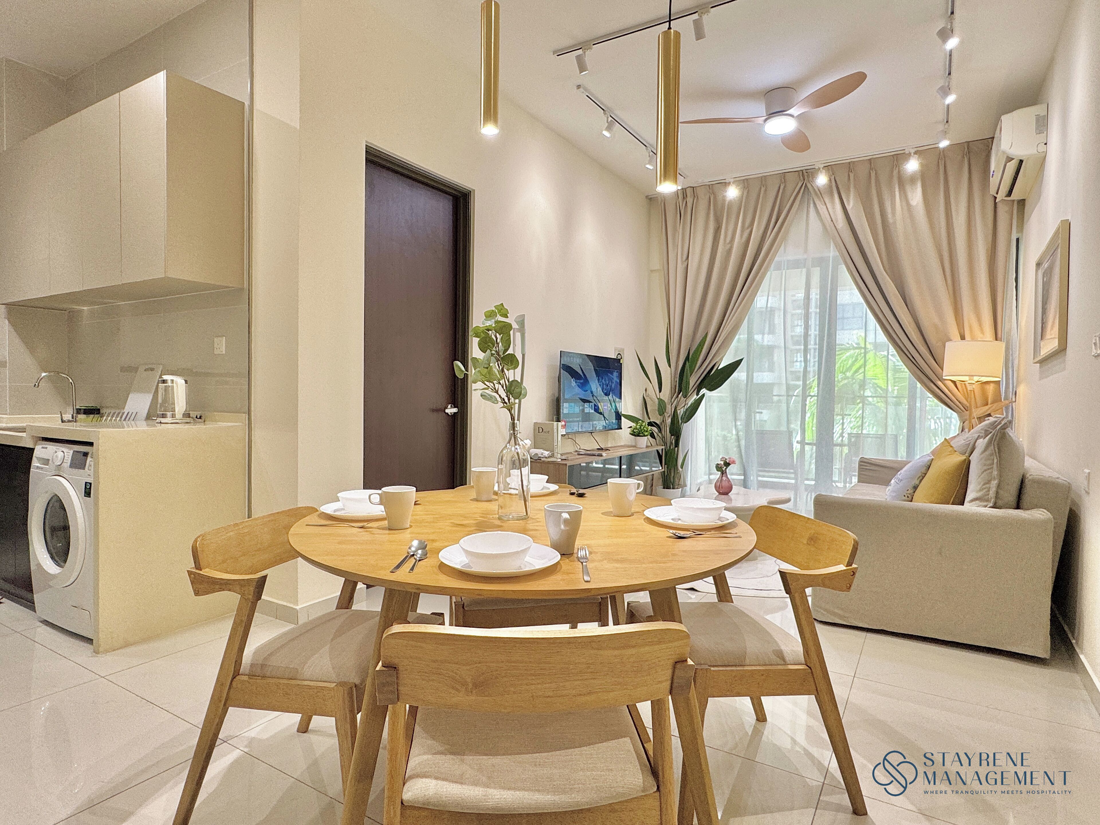 A modern dining area with a round table, wooden chairs, and a sofa in the background.