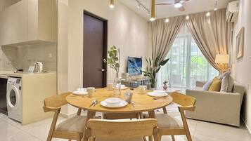 A modern dining area with a round table, wooden chairs, and a sofa in the background.