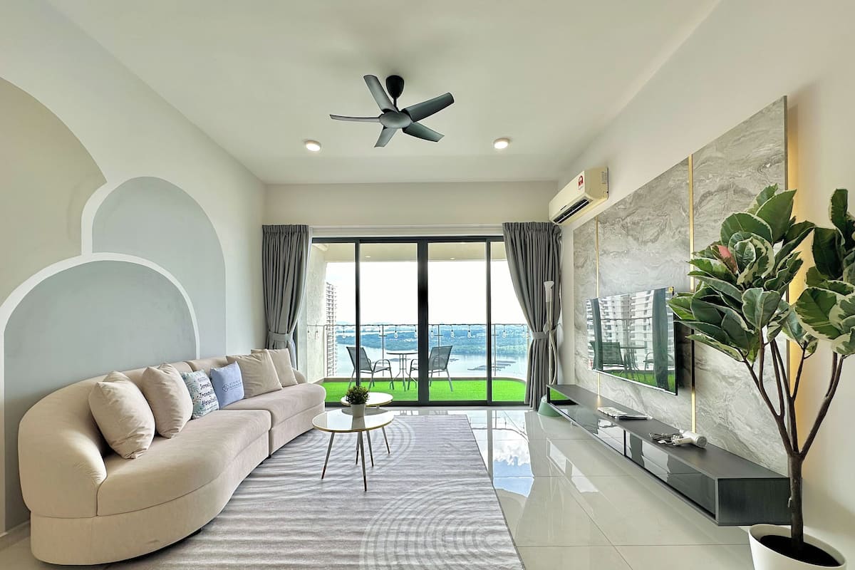 A modern living room with a sofa, a coffee table, a TV, and a balcony with a view.