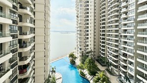 A high-rise residential building with multiple balconies, a swimming pool, and a view of the water body. - Country Garden Danga Bay By Stayrene (Johor Bahru)