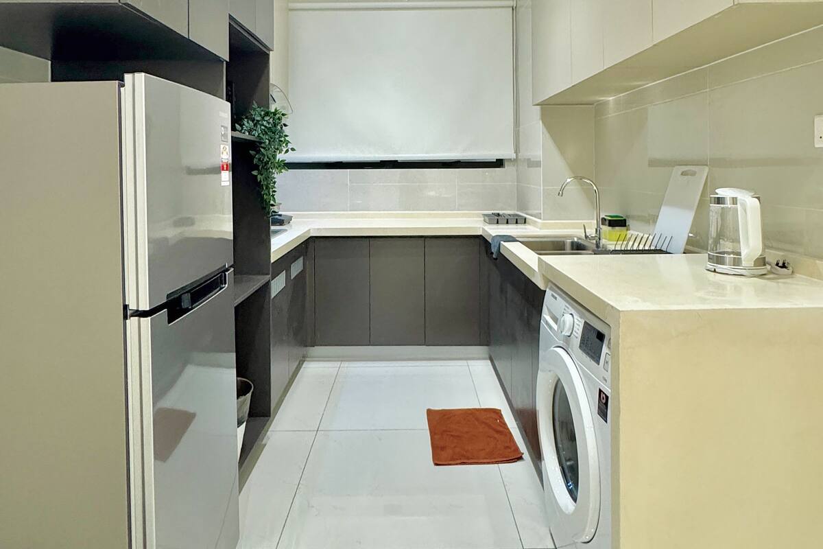 A modern kitchen with a built-in washing machine, a sink, and a countertop with a coffee maker.
