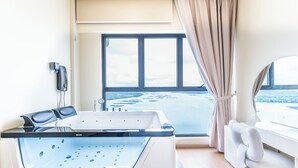 A spa room with a hot tub, a massage chair, a window with a view of the sea, and a towel rack. - Country Garden Danga Bay By Stayrene (Johor Bahru)