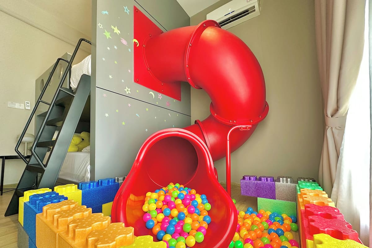 A play area with a red slide, colorful building blocks, and a staircase.