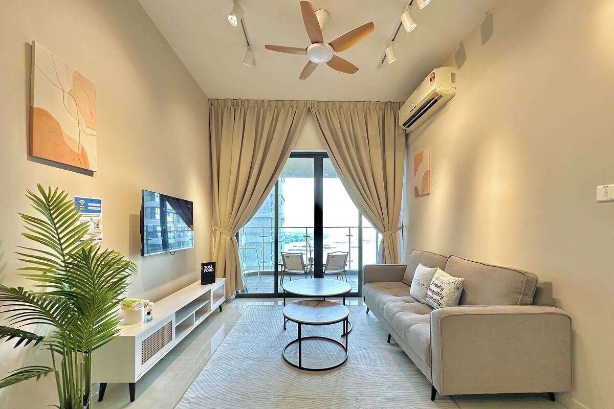 A modern living room with a sofa, two coffee tables, a TV, and a ceiling fan.
