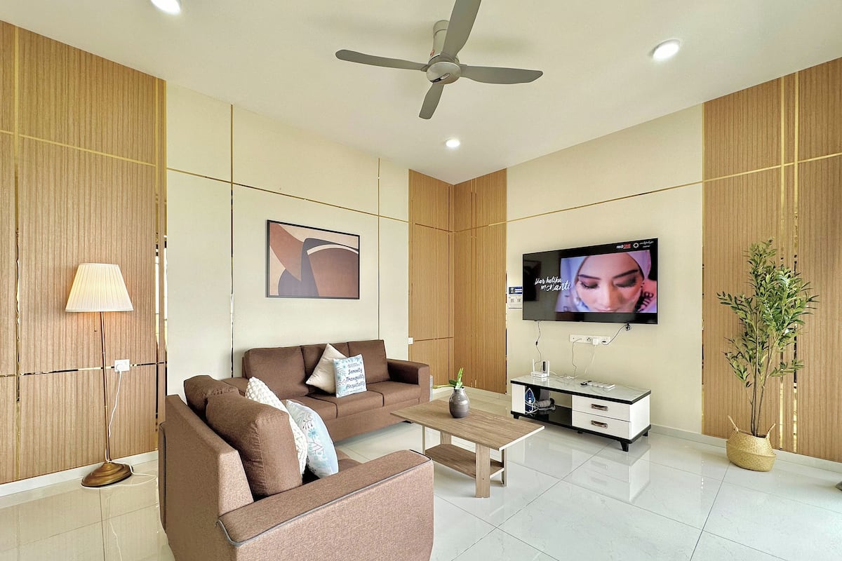 A modern living room with a sofa, coffee table, TV, and a ceiling fan.