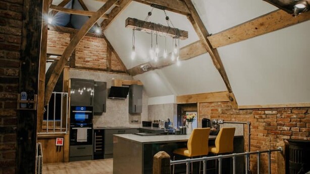 A rustic kitchen with exposed wooden beams, a central island, and modern appliances. - Urban Lofts, Melksham - Butler (Melksham)
