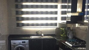 A compact kitchen with a washing machine, sink, and cabinets. - Stunning 2-bed Apartment in Lagos (Lagos)