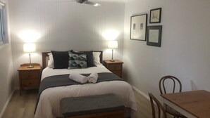 A neatly arranged bedroom with a bed, bedside tables, a desk, and a chair. -  Tangara - A Stylish Newly Renovated Studio Apartment, close to the surf beach. (Inverloch)