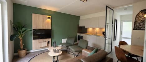 A modern living room with a sofa, chairs, a small table, and a potted plant.