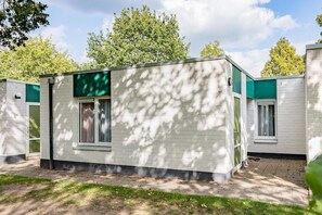 Een modern, gelijkvloers gebouw met een plat dak, grote ramen en een groene luifel.