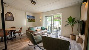 Una sala moderna con un sofá, sillas, una mesa de comedor y una planta en maceta.
