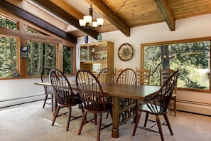 A dining area with a wooden table and chairs, large windows, and a ceiling with exposed beams. - Classic East Vail Home - Private Hot Tub Near Bus (Vail)