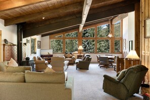 A spacious living area with multiple seating options, large windows offering a view of the outdoors, and a fireplace. - Large East Vail Chalet - Hot Tub & Close to Bus (Vail)
