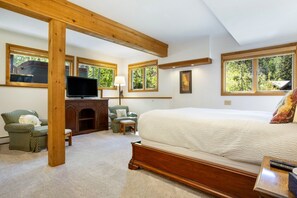 A bedroom with a large bed, wooden beams, a television, a fireplace, and multiple windows. - Large East Vail Chalet - Hot Tub & Close to Bus (Vail)