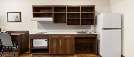 A compact kitchen with wooden cabinets, a built-in microwave, and a white refrigerator.