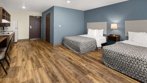 Une chambre d’hôtel avec deux lits, une kitchenette et un plancher en bois.