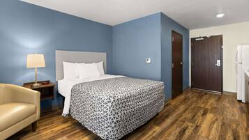 Ein Hotelzimmer mit einem Bett, einem Nachttisch, einem Stuhl und einer Tür.