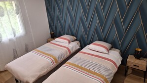 Una cama doble con una colcha estampada y dos mesitas de noche con lámparas.