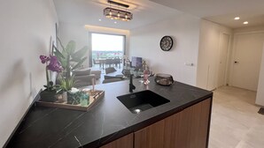 A modern kitchen with a black marble countertop, wooden cabinets, and a large window offering a view of the outdoors. - Luxurous appartment with stunning views of the golfcourse and sea  (Orihuela Costa)