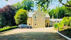 Un bâtiment en pierre avec une allée et une voiture garée.