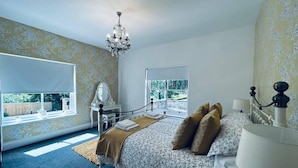 Une chambre à coucher avec un grand lit, une commode, une coiffeuse avec un miroir et un lustre.