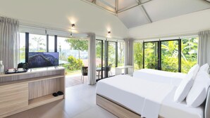 A modern hotel room with a large bed, a TV on a wooden console, a balcony with a table and chairs, and large windows with a view of greenery. - The Glamping @ARTOTEL Pelangi Park (Bogor)