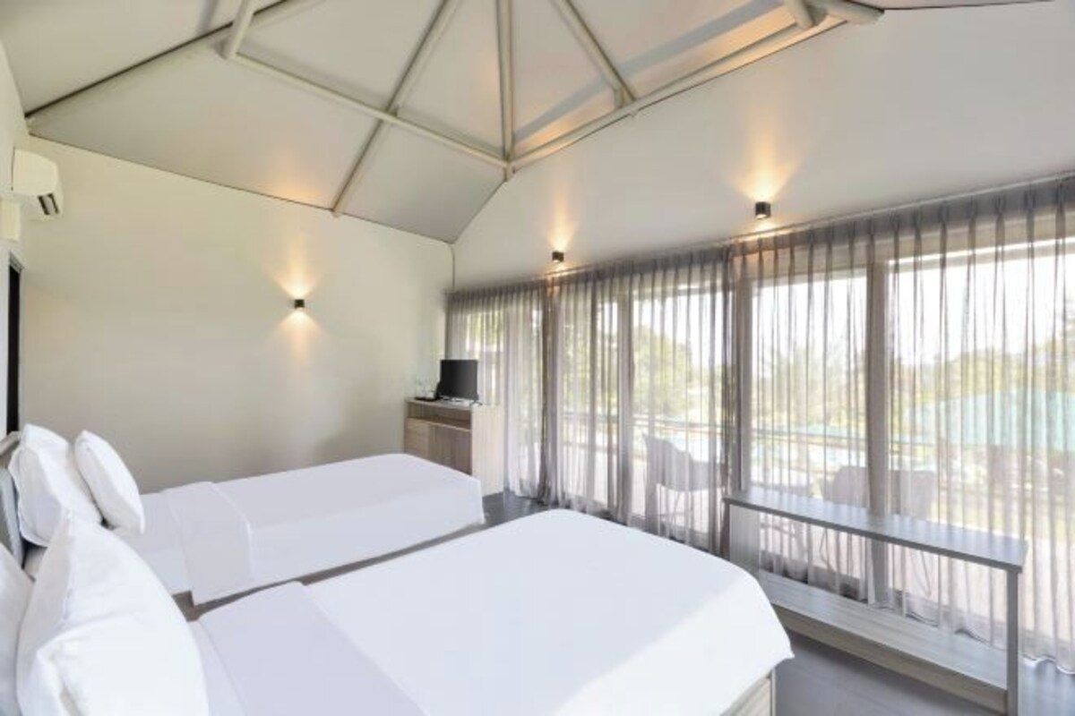 Una habitación de hotel moderna con una cama grande, un televisor y un balcón con cortinas.