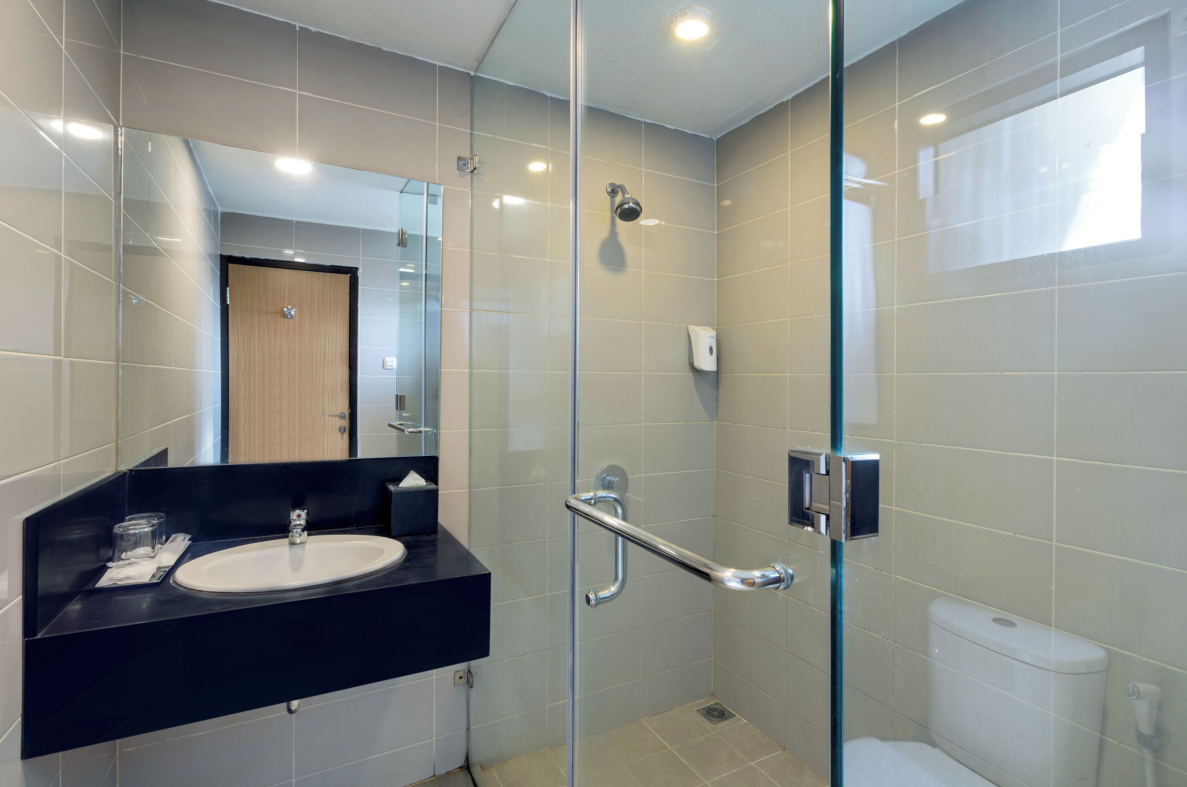 A modern bathroom with a glass-enclosed shower, a black countertop sink, and a white toilet.