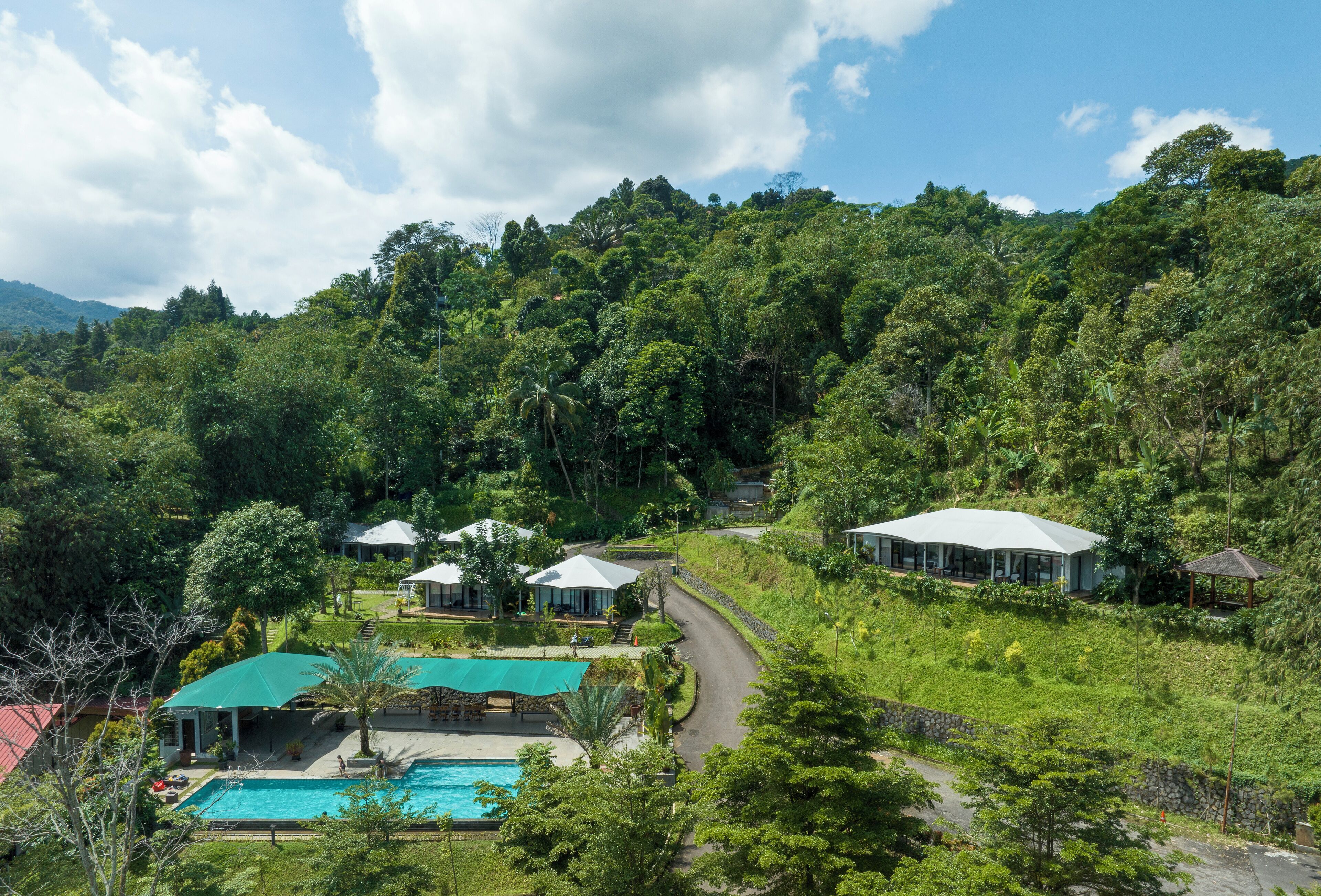 A resort with a swimming pool, multiple guest houses, and lush greenery.