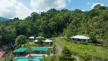 A resort with a swimming pool, multiple guest houses, and lush greenery.