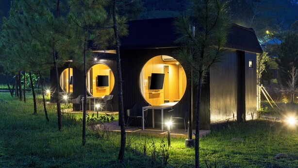 A modern, circular wooden cabin with a porch and a small table. - The Glamping @ARTOTEL Pelangi Park (Bogor)