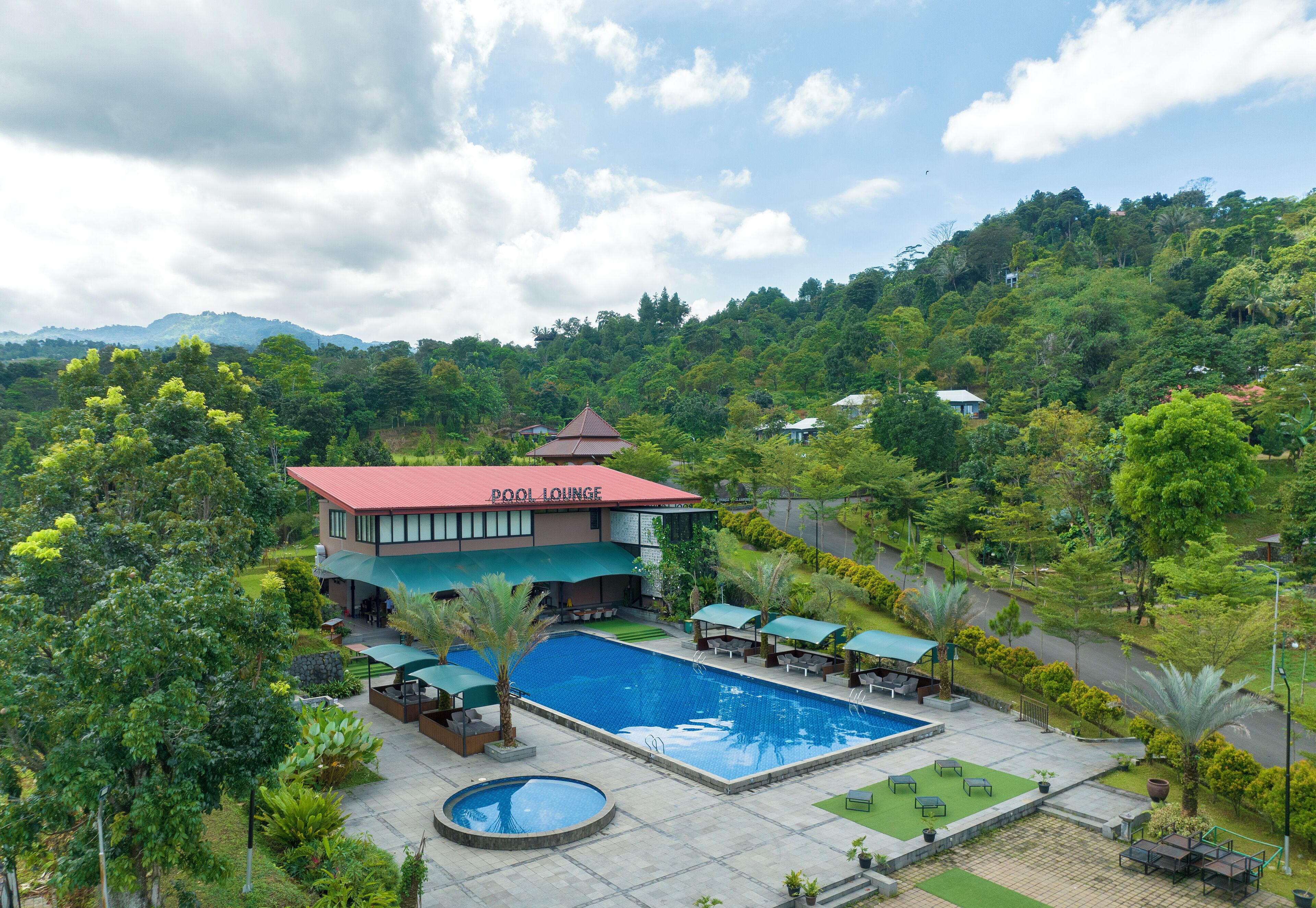 Hotel con piscina, zona de estar exterior y exuberante vegetación.